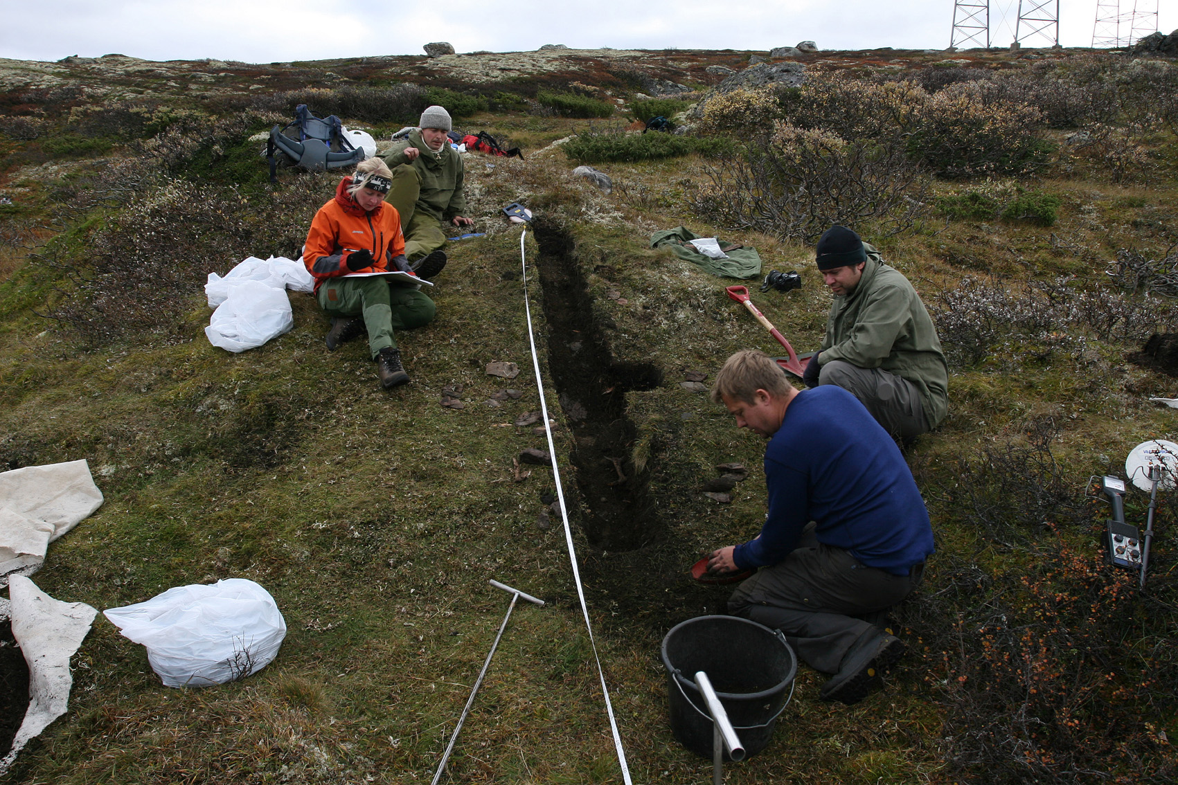 Arkeologar frå Oppland Fylkeskommune under utgraving av mødding på buplassen ved Verket-anlegget 29. september 2006. I forgrunnen fylkesarkeologane Espen Finstad og bakom Ragnar Bjørnstad, bak til venstre arkeolog Irene Skauen Sandodden og arkeologistudent Runar Hole. Sistnemnte har vore med og målt inn anlegget her. Foto: Per Jordhøy©.
